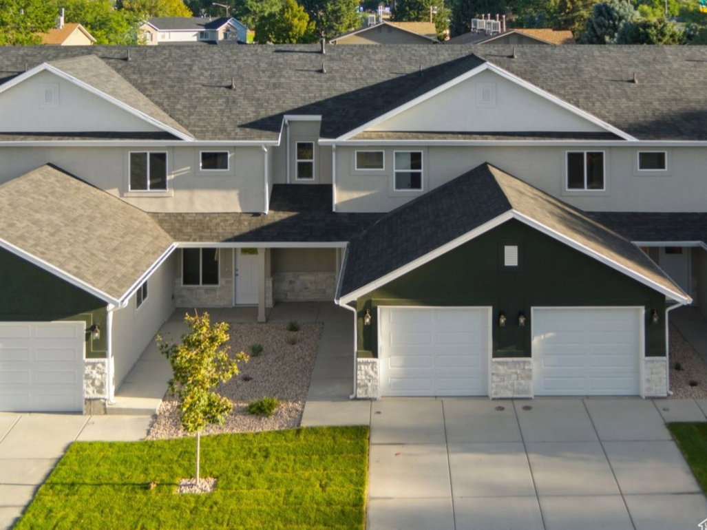 View of front facade with stone siding, roof with shingles, and stucco siding
