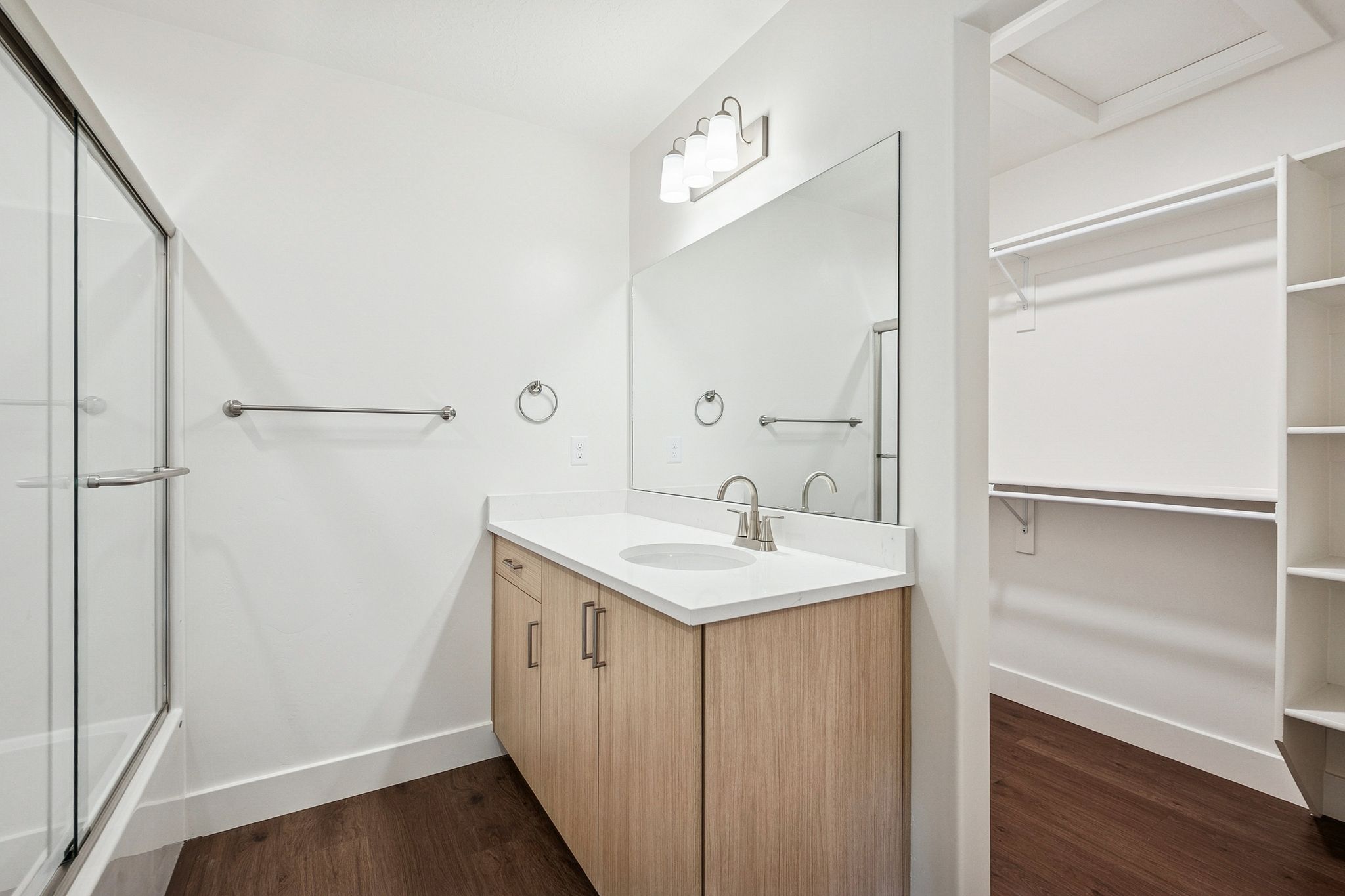 Full bath with vanity, dark wood-type flooring, a spacious closet, and enclosed tub / shower combo