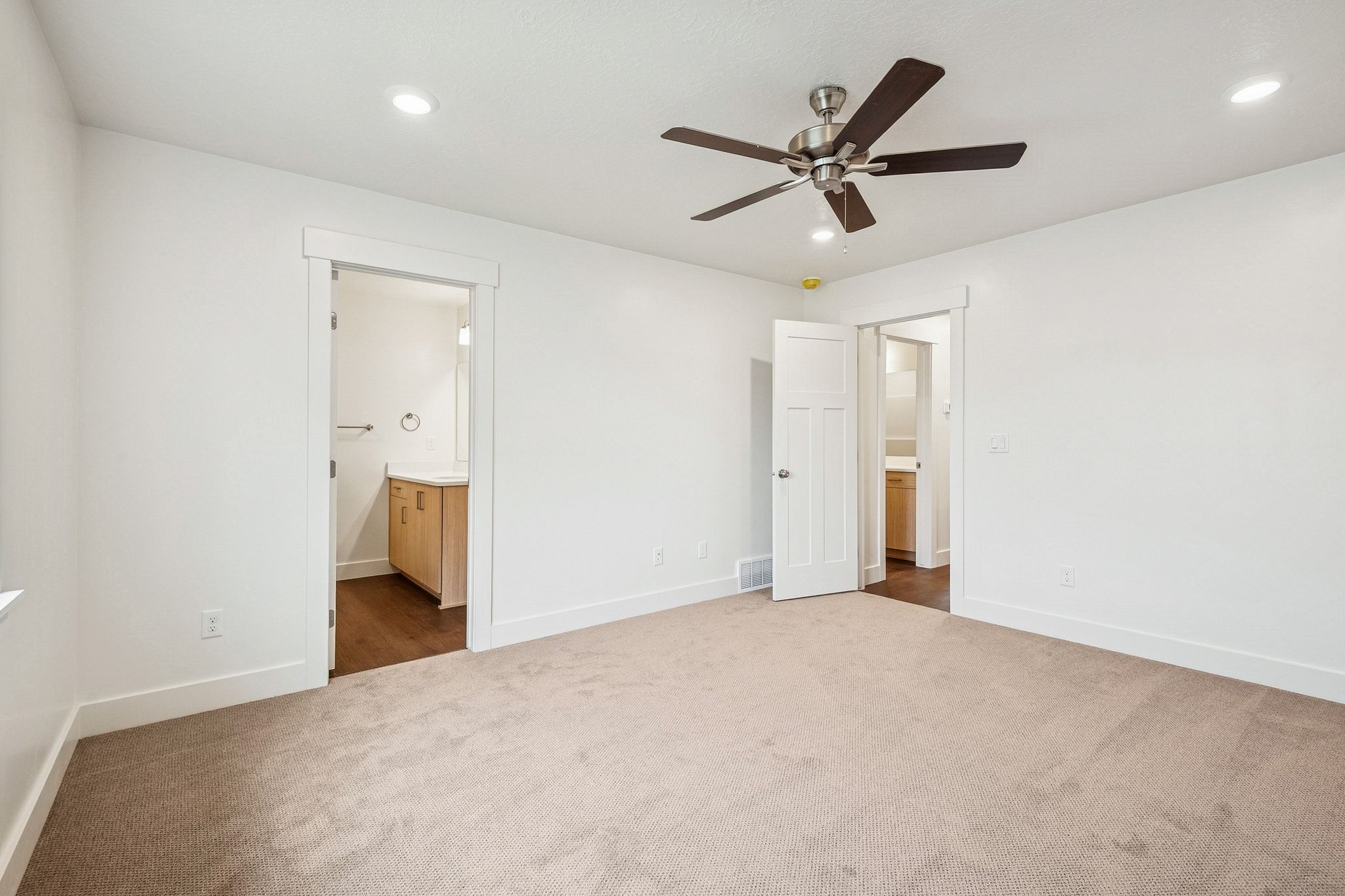 Unfurnished bedroom featuring ensuite bathroom, dark carpet, a ceiling fan, and recessed lighting