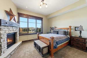 Bedroom featuring light carpet and a stone fireplace