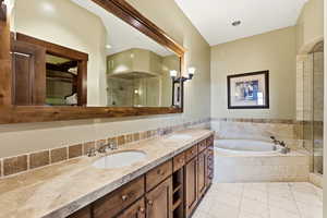Full bath featuring double vanity, a bath, a shower stall, light tile patterned flooring, and a walk in closet