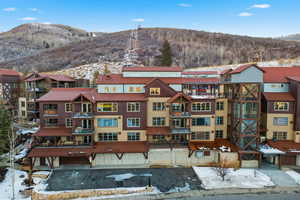 Snowy aerial view with a mountain view and a view of apartment building / complex