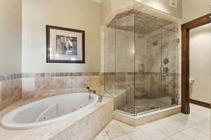 Bathroom with a tub with jets, a stall shower, and tile patterned floors
