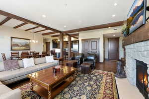 Living area featuring beamed ceiling, a stone fireplace, a chandelier, recessed lighting, and wood finished floors