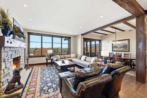 Living room featuring wood-type flooring, recessed lighting, a fireplace, beam ceiling, and a chandelier