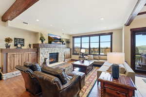 Living room featuring beam ceiling, a fireplace, wood-type flooring, and recessed lighting