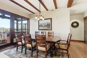 Dining area with beam ceiling, a chandelier, light wood finished floors, a mountain view, and recessed lighting