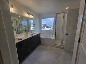 Full bath featuring a stall shower, double vanity, light marble finish floors, a bath, and recessed lighting