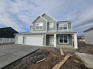 Craftsman-style home with covered porch, concrete driveway, a metal roof, a standing seam roof, and board and batten siding