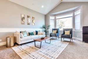 Carpeted living area with lofted ceiling and baseboards