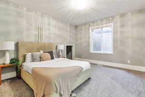Carpeted bedroom featuring baseboards and a textured ceiling