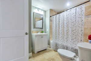 Full bath with vanity, shower / tub combo with curtain, and light tile patterned floors