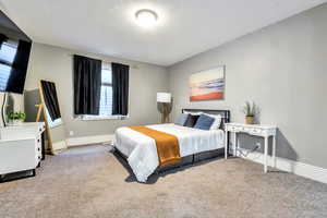 Carpeted bedroom featuring baseboards and a textured ceiling