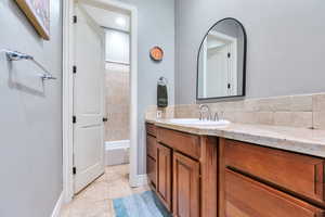 Full bath featuring vanity, light tile patterned floors, and washtub / shower combination