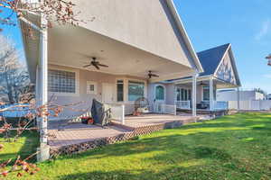 Rear view of house with ceiling fan, a yard, stucco siding, and a deck
