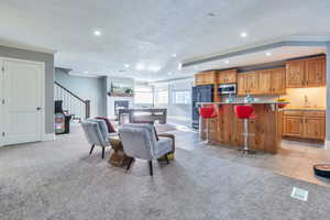Living room with recessed lighting, light tile patterned floors, ornamental molding, a glass covered fireplace, and stairway