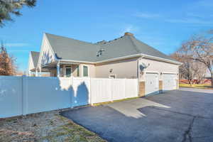 View of home's exterior with a shingled roof, asphalt driveway, an attached garage, and stucco siding
