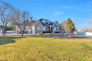 View of front of house featuring driveway, a chimney, stone siding, and a garage