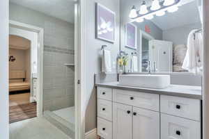 Full bath featuring vanity, a textured ceiling, a tile shower, and ensuite bathroom