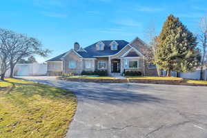 Craftsman house with stone siding, a front lawn, driveway, and a chimney