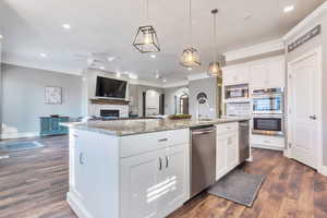 Kitchen featuring decorative light fixtures, white cabinetry, open floor plan, light stone counters, and ceiling fan