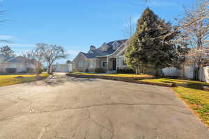 Cape cod house with a garage, brick siding, driveway, and a chimney