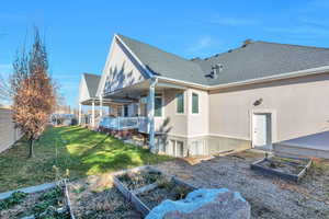 Back of property featuring a vegetable garden, a shingled roof, a deck, ceiling fan, and stucco siding