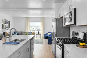 Kitchen featuring stainless steel appliances, open floor plan, white cabinetry, a textured ceiling, and light wood finished floors