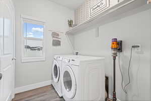 Laundry room with wood finished floors and washer and dryer