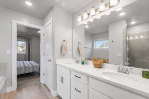 Full bath featuring double vanity, a shower stall, light wood-style floors, recessed lighting, and ensuite bath