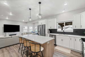 Kitchen with a breakfast bar, white cabinets, a kitchen island, pendant lighting, and recessed lighting