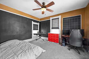 Carpeted bedroom with a ceiling fan and an office area