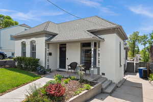 View of front of house featuring stucco siding, a porch, and a shingled roof