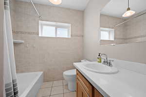 Bathroom with vanity, shower / tub combo, light tile patterned floors, and healthy amount of natural light