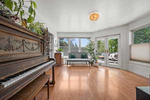 Sitting room featuring light wood-style flooring, healthy amount of natural light, and french doors
