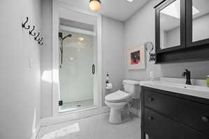 Full bath with vanity, a stall shower, and tile patterned floors