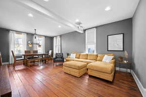 Living room featuring recessed lighting, dark wood-style flooring, and beam ceiling