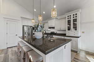Kitchen featuring decorative light fixtures, stainless steel appliances, a kitchen bar, a chandelier, and an island with sink