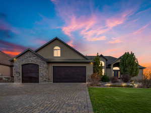 View of front of house with stucco siding, a garage, a front lawn, and decorative driveway