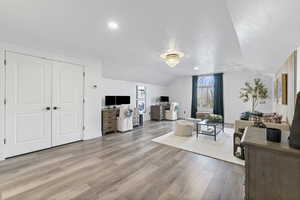 Living area with lofted ceiling, light wood-type flooring, a desk, and recessed lighting