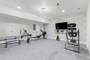 Exercise area with brick wall, electric panel, and recessed lighting
