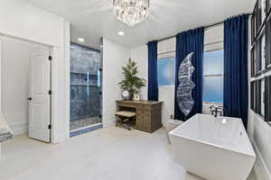 Full bathroom featuring a freestanding bath, a stall shower, a chandelier, recessed lighting, and light tile patterned floors