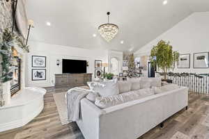 Living room featuring wood-type flooring, high vaulted ceiling, a chandelier, and recessed lighting