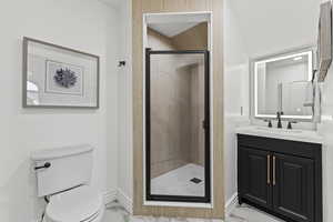 Bathroom featuring light marble finish flooring, vanity, and a stall shower
