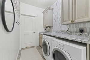 Laundry area featuring separate washer and dryer, cabinet space, and light tile patterned flooring