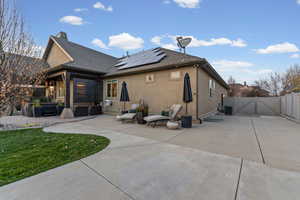 Back of house with a gate, solar panels, a fenced backyard, and stucco siding