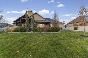 Back of house with a chimney, stucco siding, and solar panels