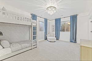 Carpeted bedroom featuring baseboards and a chandelier