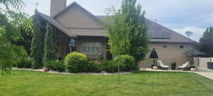 Rear view of property with stucco siding, a lawn, and a patio area