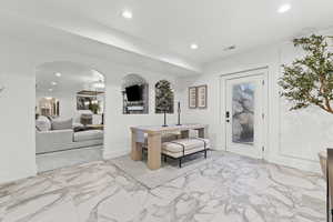 Foyer featuring light marble finish flooring, recessed lighting, and arched walkways